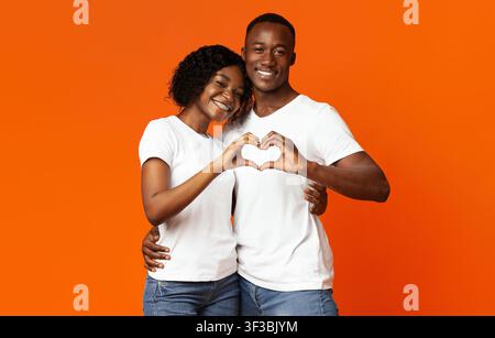 Smiling african lovers making heart shape gesture with hands Stock Photo