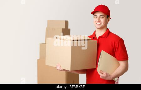 Courier and package in warehouse. Deliveryman holding box and tablet near stack of parcels Stock Photo