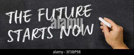Text written on a blackboard - The Future Starts Now Stock Photo