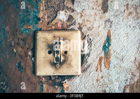 An old Soviet light switch on a peeling wall Stock Photo