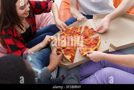 Students sharing pizza at home party Stock Photo