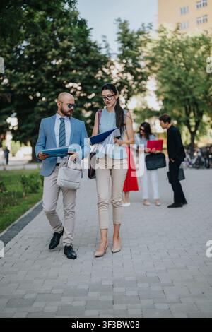 Business colleagues walking and discussing documents outdoors in a casual urban setting Stock Photo
