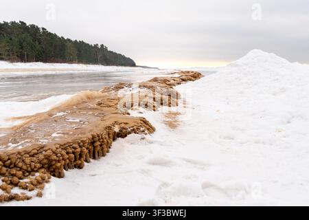 Frozen Sandy Ice Formations Along Winter Seashore With Snowdrifts and Forest Coastline, Cold Baltic Landscape Showing Natural Erosion, Texture and Qui Stock Photo