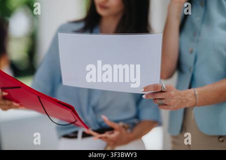 Two colleagues reviewing a printed business report with charts during an informal meeting Stock Photo