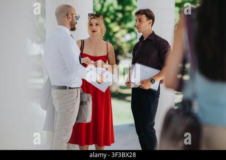 Three colleagues having a professional outdoor conversation while reviewing documents in summer Stock Photo