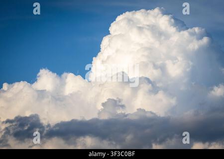 Bright cumulus towers glow above a line of darker clouds creating a layered sky that suggests shifting weather and adds drama to the peaceful blue of Stock Photo