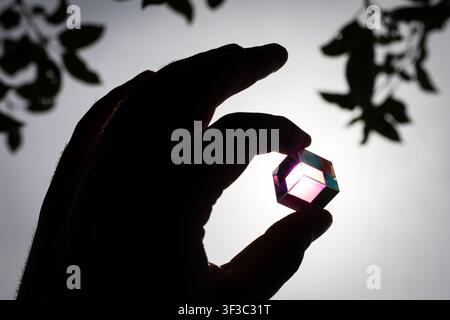 Compact glass cube shows shifting hues when held to the sun conveying STEM curiosity imagination and the joy of tinkering suited to education marketin Stock Photo