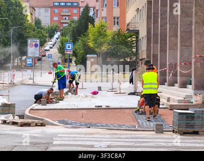 Construction workers paving a sidewalk on a city street Stock Photo