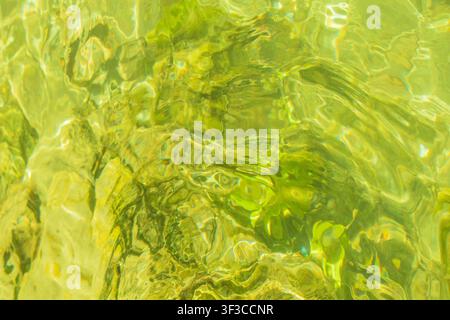 Top view flat lay of golden lime green water surface with rippled texture pattern for natural abstract background design concept with vibrant liquid b Stock Photo