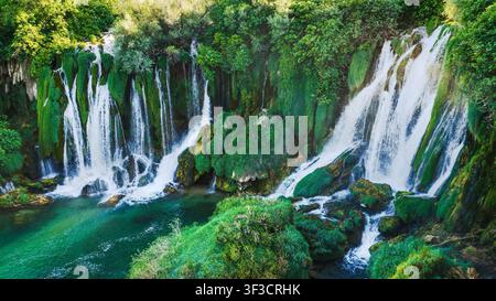 Close view of powerful cascading waterfalls flowing over moss covered rocks Stock Photo