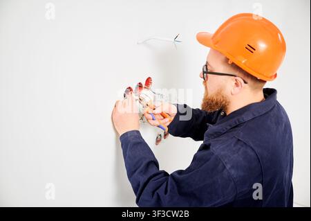 Worker using wire stripper to prepare electrical cables for socket installation. Close up of repair process, electrical maintenance and home improvement concept Stock Photo