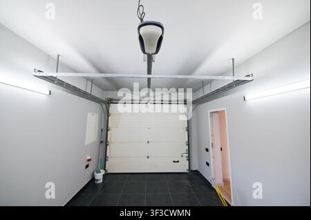 Spacious empty garage room with automatic gate, bright walls and ceramic floor tiles. Residential parking, storage, renovation and real estate concept Stock Photo