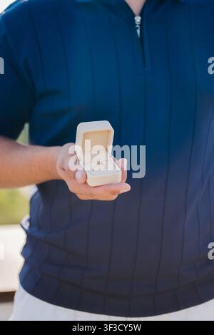 Man with a big bouquet of white roses standing on a rooftop terrace over a river and city skyline on a sunny summer day, a romantic proposal concept Stock Photo