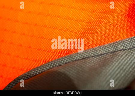 A high visibility orange fabric texture with close up stitching and gray binding edge, rugged woven material showing detailed weave and durable outdoo Stock Photo