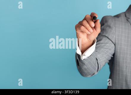 Closeup of businessman with marker writing or drawing on virtual screen against blue background, empty space Stock Photo