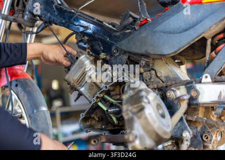 A motorcycle engine repair in workshop with mechanic hands working on disassembled small motorcycle engine, gritty detail and focused maintenance scen Stock Photo