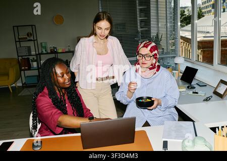 Diverse Women Collaborating on Laptop in Modern Office Stock Photo