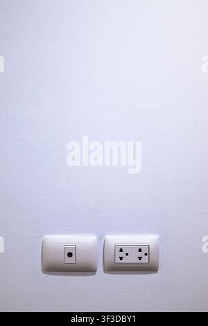 Minimalist interior white wall featuring a double electrical power outlet and a coaxial TV antenna jack at the bottom, with large vertical blank copy Stock Photo