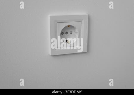 A electrical power outlet is mounted on a plain white wall in a modern home. Stock Photo