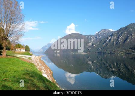 The picturesque Lake Idro in the Italian Alps with clear water reflecting the surrounding mountains on a sunny day. Stock Photo