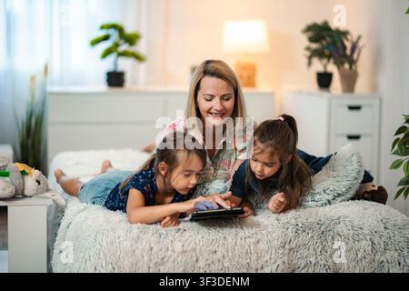 Mother and daughters learning together using digital tablet Stock Photo