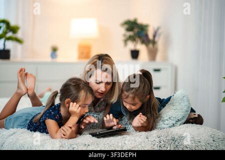 Mother and children using digital tablet in bed Stock Photo