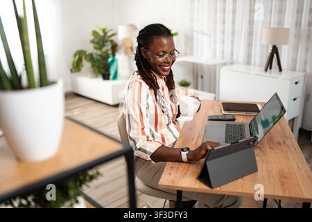 Black woman working from home using laptop tablet Stock Photo