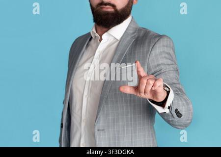 Cropped view of young entrepreneur touching imaginary screen over blue background, blank space Stock Photo