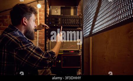 Male technician verifying server rack status with mobile device in technical room Stock Photo