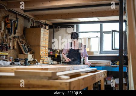 Craftsmanship, renovation and working process, woman carpenter restoring old wooden door in workshop Stock Photo