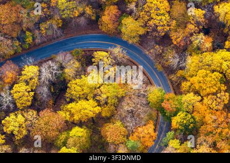 Peaceful mountain pass road winding through colorful autumn woods. Beautiful seasonal scenery with no traffic or people. Stock Photo