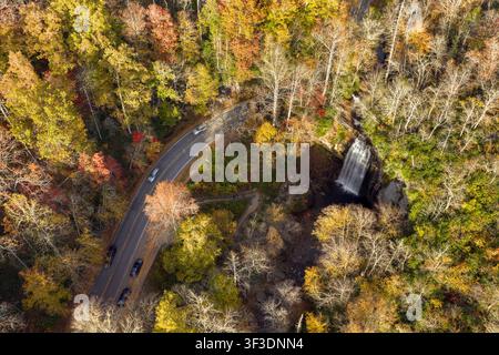 Forest Heritage Scenic Byway and Looking Glass Falls with visitors on the overlook. Cars driving along the scenic roadway through colorful autumn Stock Photo