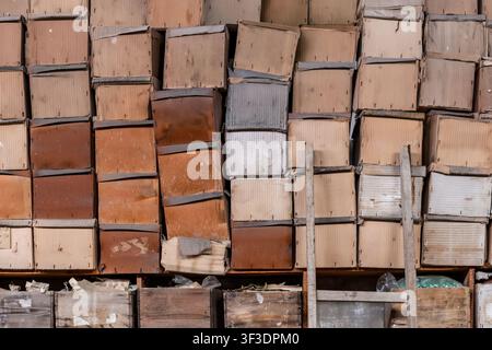 Wall of aged cardboard boxes stacked in a warehouse creating a repeated geometric pattern. Warm soft light, beige-brown tones. Evokes archiving, histo Stock Photo