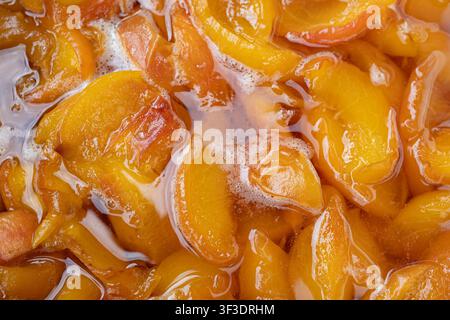Close up texture of homemade peach jam with juicy fruit pieces in sweet syrup. Natural fruit preserve background for food design, packaging and recipe Stock Photo