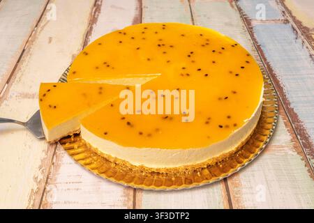 Sliced Passion Fruit Cheesecake with Glossy Fruit Glaze and Biscuit Crust on Gold Board Stock Photo