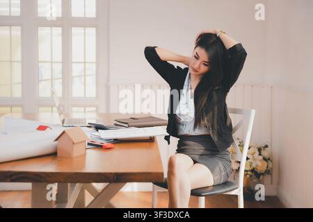 Office syndrome concept. Business Woman stretching her neck to relieve fatigue , suffering from pain after sedentary working in incorrect posture for Stock Photo