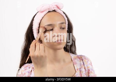 Young attractive woman applying face powder brush on cheek for makeup Stock Photo