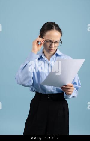 Smart young businesswoman holding paper documents reading contract carefully Stock Photo