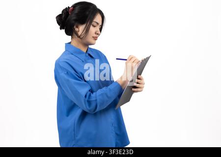 Focused office worker taking notes on a clipboard during daily tasks Stock Photo