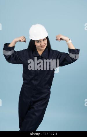 Confident female builder flexing her muscles to show strength Stock Photo
