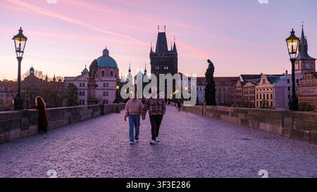 As the sun sets over Prague, a couple walks hand in hand on a cobblestone street, surrounded by stunning old buildings and warm street lamps. The drea Stock Photo