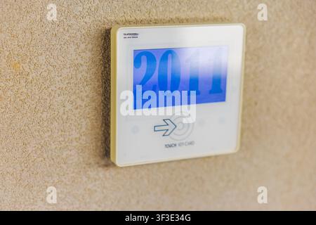 Close-up view of hotel room number display with RFID key card access panel on textured wall. Crete. Greece. Stock Photo