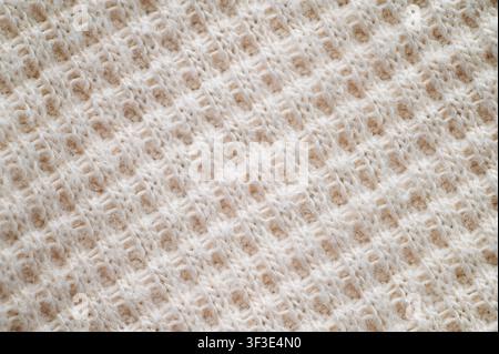 Macro close-up of soft wool knitted fabric with visible stitches and fibers. Stock Photo