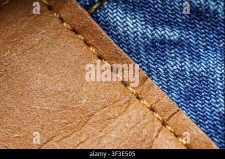 Close-up of brown leather patch stitched to blue denim with golden thread. Stock Photo
