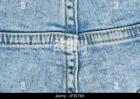 Close up light blue denim fabric with double orange stitching seams forming cross Stock Photo