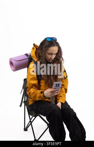 Relaxed traveler sitting on camping chair holding smartphone Stock Photo