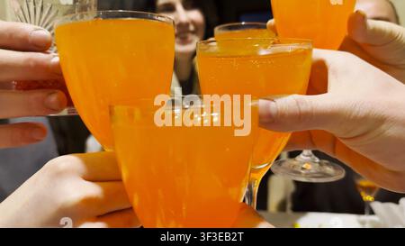 Female and male hands holding glasses gather in center as they toast together during festive gathering. The glasses clink, capturing joyful moment of Stock Photo