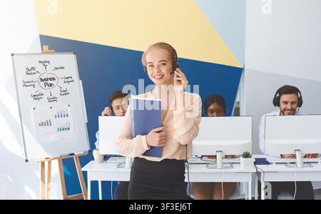 Portrait of happy female customer support operator and her coworkers at office Stock Photo