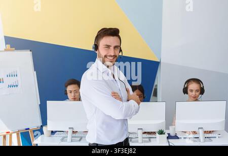 Happy male customer support executive and his colleagues at call centre office Stock Photo