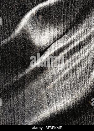 This image features a textured grey surface dramatically illuminated by strong diagonal light and shadow patterns Stock Photo